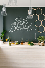 A graphite wall and a light wooden kitchen. Decor and kitchen utensils on the table