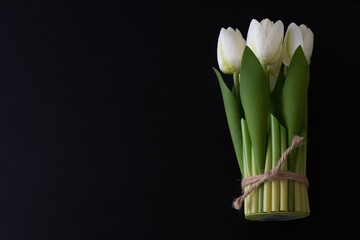 White artificial flowers of tulips on black background. Side view, place for text, banner. Gift for holiday. 