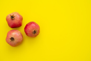 Three juicy and ripe pomegranates on yellow background. Fruits contain many vitamins. healthy fruits:  good for healthy lifestyle.  food for diet. place for text. Close up.