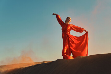 Woman in red dress dancing in the desert