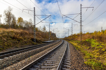 Fototapeta na wymiar Rural autumn landscape on empty railroad in Siberia. Railroad tracks receding into the distance. Industrial landscape with wooden railway platform