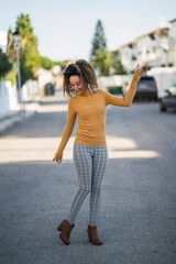 Chica delgada con pelo rizado posando en la calle