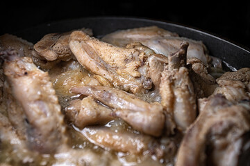 Chicken wings are cooked in their own juice in a pan