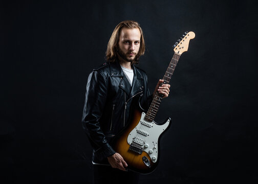 bearded rock musician playing electric guitar in leather jacket, rock music