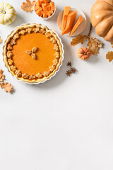 Obraz na płótnie Canvas Traditional American Pumpkin Pie on white background. View from above. Homemade pastry for Thanksgiving Day. Vertical format with space for text.