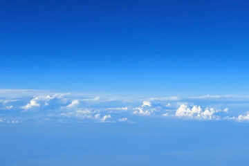 Naklejka na ściany i meble View from an airplane porthole to the beautiful white clouds and clear blue sky