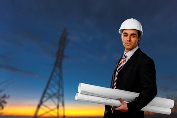 An electrician on the background of high towers of power plants looks at the project concept