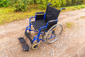 Empty wheelchair standing on road waiting for patient services. Invalid chair for disabled people parked outdoor in nature. Handicap accessible symbol. Health care medical concept.