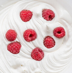 Fresh raspberries in the yoghurt or cream. Top view.