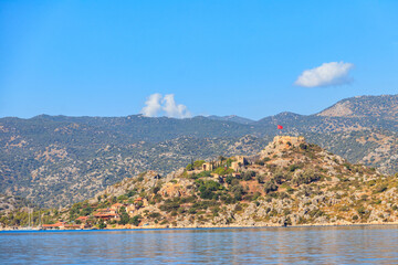 Fototapeta na wymiar View of ancient Lycian town Simena with fortress on a mount on the coast of the Mediterranean sea in Antalya Province, Turkey