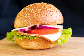burger with meat cheese tomato onions on a board on a black background