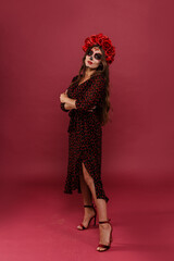 Mexican woman in dress dances at national holiday Santa Muerte in mask in form of skull