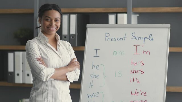 Online schooling concept. Young confident professional african american woman teacher posing near whiteboard and smiling