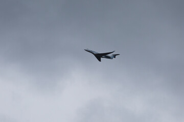 Silhouette of private Jet up in the sky against dark gray clouds