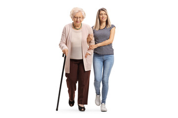 Full length portrait of a young woman helping an elderly woman and walking towards camera - obrazy, fototapety, plakaty