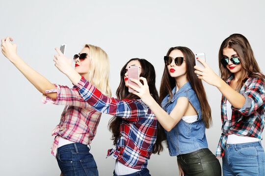 friendship, people and technology concept - four happy teenage girls with smartphone taking selfie