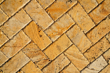 Yellow brown stone pavers background. Neutral texture of a flat brick wall close-up.        