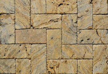 Yellow brown stone pavers background. Neutral texture of a flat brick wall close-up.        