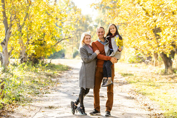 Picture of lovely family in autumn park, young parents with nice adorable kid playing outdoors, have fun on backyard in fall, happy family enjoy autumnal nature