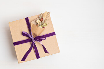Gift box with velvet ribbon and dried flowers bouquet. Creative and zero waste holidays present wrapping. Womens day, mothers day, thanksgiving, easter greeting concept. Top view, flat lay
