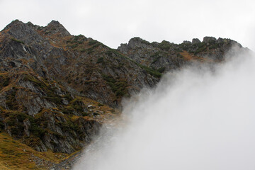 Fototapeta premium a mountain ridge emerging from the layer of clouds