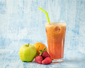 Energizing and refreshing apple, strawberry and orange mix juice on blue stone background