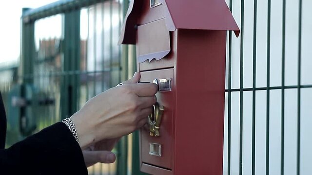 A woman opens a beautiful mailbox in front of the house with a key, sees that it is empty, leaves, disappointed. The Concept Of Important News. The News Was Waiting.