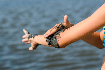 Close up of elbow joint treatment process with natural black curative mud. Alternative medicine. Selective focus