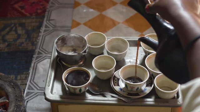 Ethiopian pouring coffee from a jebena