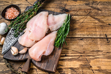 Fresh Raw sliced cut chicken breast fillet steaks on a wooden cutting board with kitchen knife....