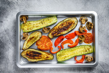 Roasted vegetables on a baking pan. White background. Top view