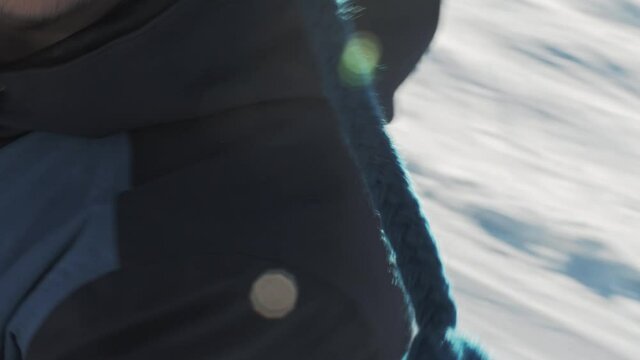 POV on A snowboarder climbing on a T-shaped lift with open arms and a desire to hug on a sunny winter day at a ski resort. Going up to the top of the slope on a tow lift.