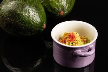 Avocado homemade ice cream in a purple pot on the black background