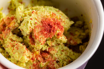 Avocado homemade ice cream in a purple pot on the black background