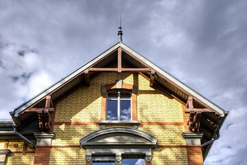 Attic of yellow brick house in sunshine and clouds