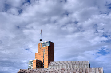 Industrial orange skyscraper in sunshine and white clouds