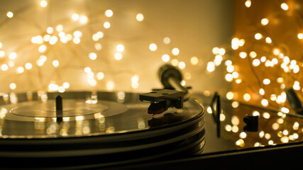 Close-up of a record on a vinyl record player. Bokeh of led lights garlands in the background.