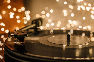 Close-up of a record on a vinyl record player. Bokeh of led lights garlands in the background.