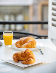 French breakfast, fresh baked croissant buttery pastry served with orange juice and old french houses on background