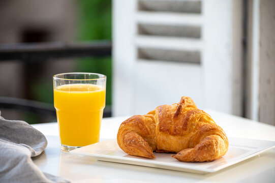 French breakfast, fresh baked croissant buttery pastry served with orange juice and old french houses on background