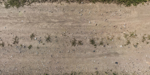 top panorama view from above on surface of gravel road with car tire tracks