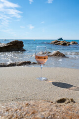 Summer time in Provence, glass of cold rose wine on sandy beach and blue sea near Saint-Tropez, Var department, France