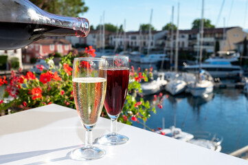 Summer party with kir royal cocktail, pouring of French brut champagne sparkling wine and cold creme cassis in glasses in yacht harbour of Port Grimaud near Saint-Tropez
