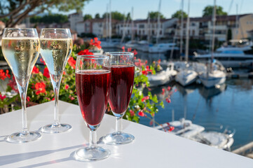 Summer party with kir royal cocktail, tasting of French brut champagne sparkling wine and cold creme cassis in glasses in yacht harbour of Port Grimaud near Saint-Tropez
