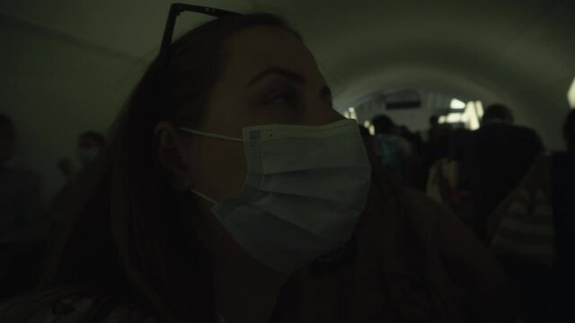 passengers in medical masks ride up the escalator in the subway during rush hour