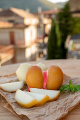 Cheese collection, variety of Italian cow milk cheese scamorza with Italian houses on background