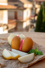 Cheese collection, variety of Italian cow milk cheese scamorza with Italian houses on background