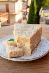 Cheese collection, piece of matured cow cheese pasmesan parmigiano reggiano and Italian houses on background