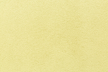 Sample of a texture of yellow plaster. Wall finished with a decorative cement stucco. Example of exterior building decoration. Clean uniform grainy background. Banner. Wallpaper. Copy space. Pattern
