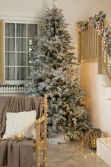 Christmas tree by the window is decorated with lights near the stairs in the courtyard. New Year's decor of the facade of the house